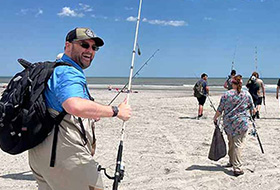 Adam Aguiar with a fishing pole on the beach