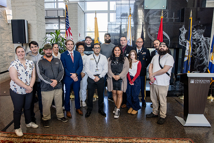 Faculty, staff and students pose during a Veterans Day ceremony in the Campus Center Grand Hall