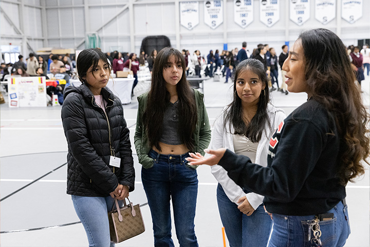 Leilani Moreno chats with three prospective students in the Sports Center