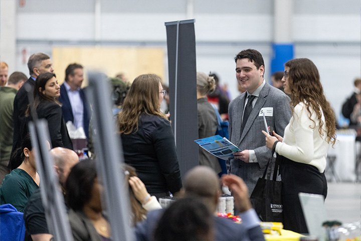 Students in business attire converse with a potential employer in Stockton's Sports Center
