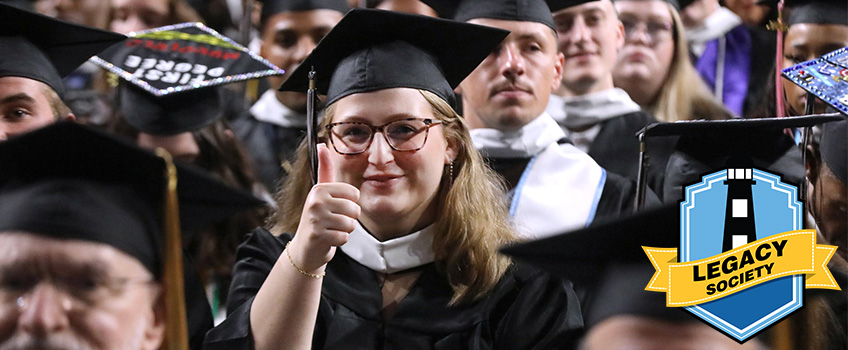A graduate giving a thumbs up to the camera during their Commencement ceremony