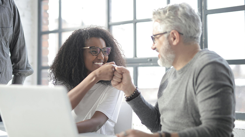 A student fist-bumping with an older adult