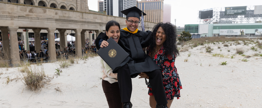 family members hold up their Stockton graduate in celebration