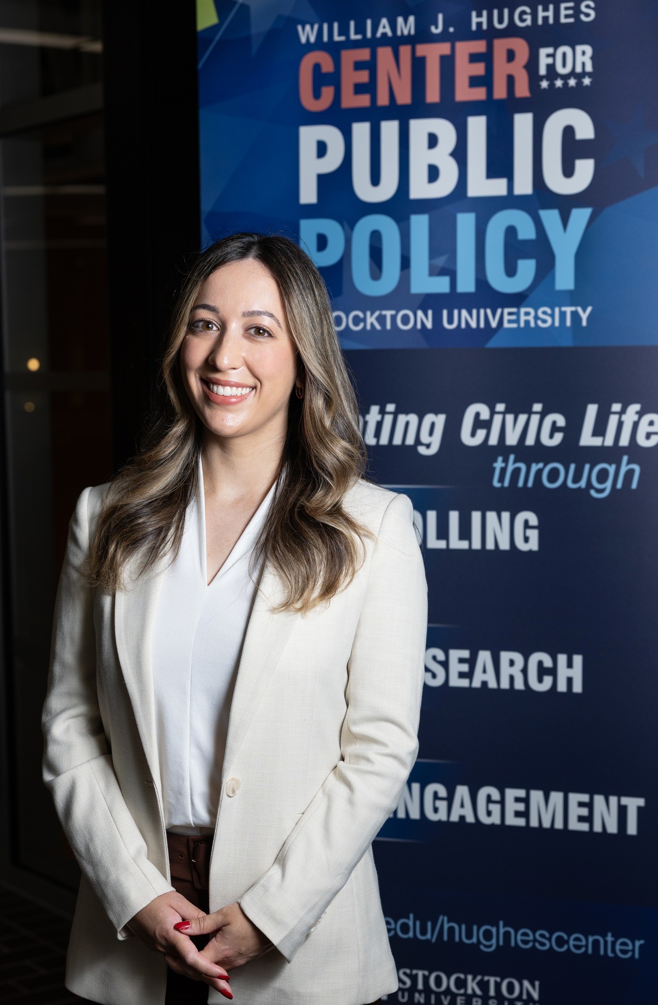 Alyssa Maurice standing in front of the Hughes Center banner bug