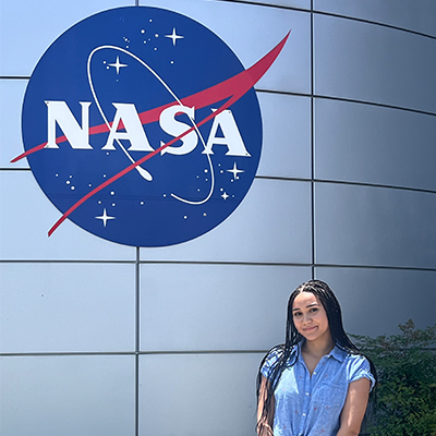 Abby posing in front of NASA's logo