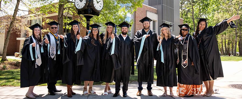 Graduates pose and smile outside