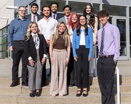Stockton School of Business Chapter of Beta Gamma Sigma graduates pose on stairs outside