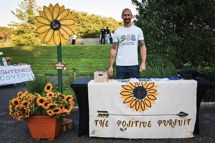 Jared Lombardi stands behind a table decorated with sunflowers