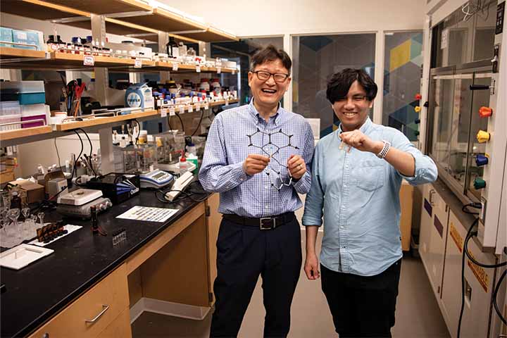 Daniel Ki holding a model of a chemical compound and Andrew Wu holding two test tubes