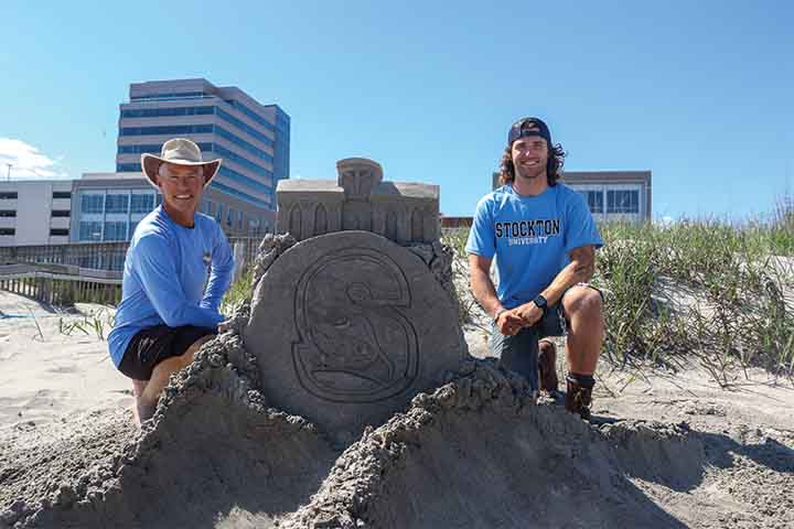 Matthew and Liam Deibert pose with a sand sculpture of Stockton's Campus Center and S logo