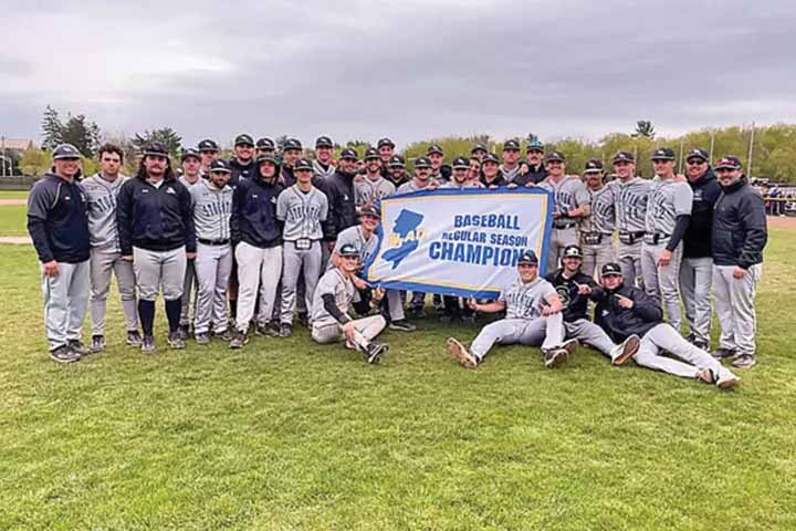 The Stockton baseball team pose on the field with their Baseball Regular Season Championship banner