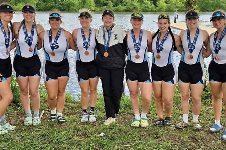 The women's rowing varsity 8 team with their bronze medals