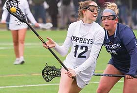 A Stockton women's lacrosse player defends the ball from an opponent