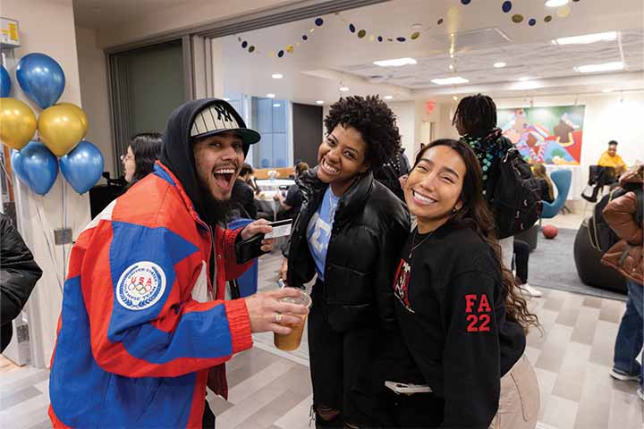 One male and two female students pose with a smile in the Multicultural Center with balloons and other party decorations