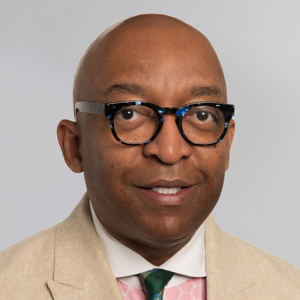 Dr. William U. Latham in glasses, a tan jacket, pink and white dress shirt, and green tie. 